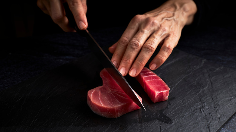 Hands cutting raw bluefin tuna