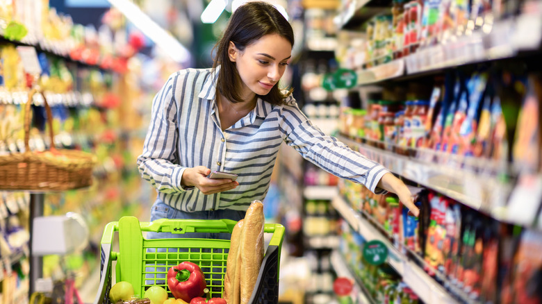 woman picking food off grocery store shelf