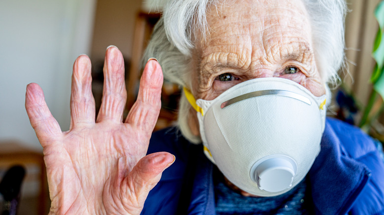 elderly woman with mask waving