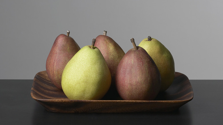 Variety of pears in wooden dish on black table