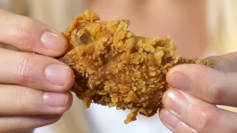 Hands holding KFC chicken wing