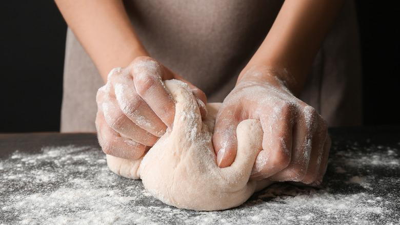 hands kneading pizza dough