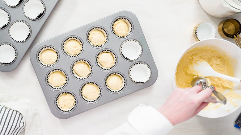 Person filling cupcake trays