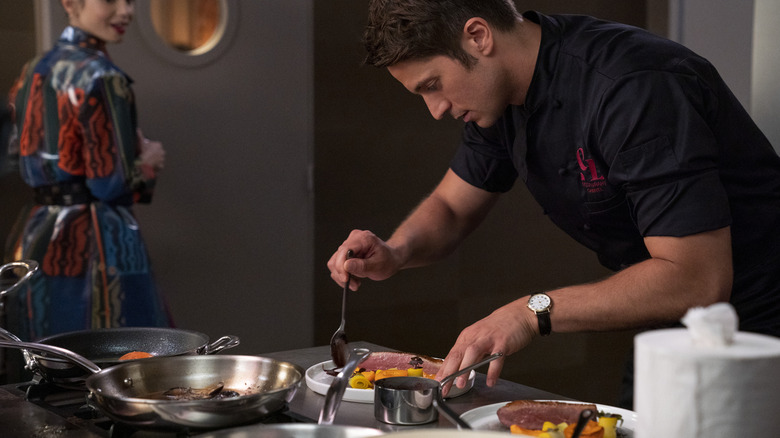 Gabriel plating food as Emily walks by