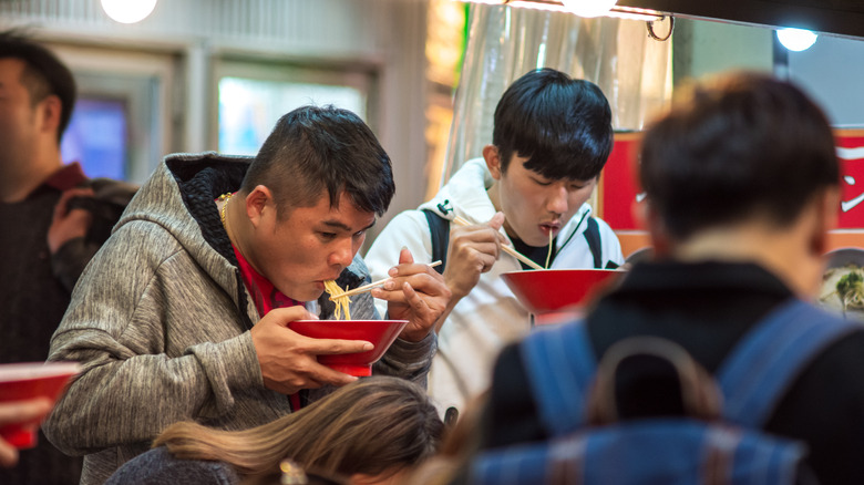 Men slurping ramen in restaurant