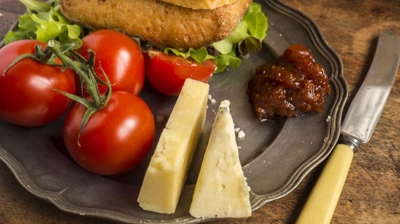 Tomatoes, cheese, and chutney on a pewter plate