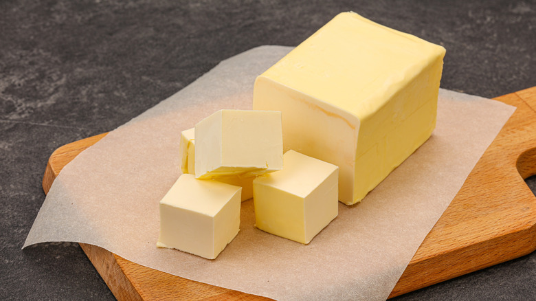 Butter cubes on a wooden cutting board with parchment paper