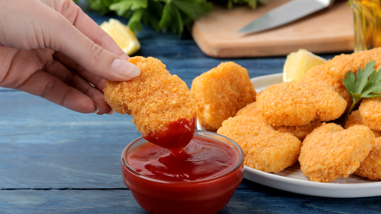 Woman dipping chicken nugget in ketcup