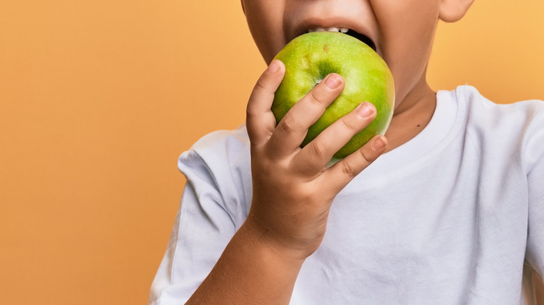 young boy eating green apple