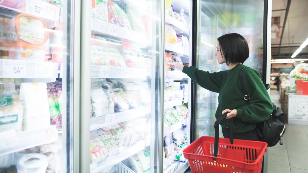 A woman searches for sliders in the grocery store freezer aisle.