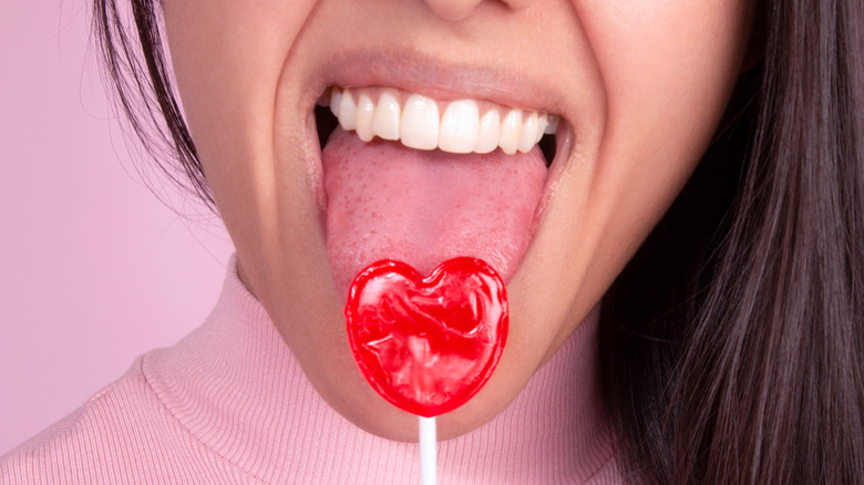 girl licking red heart-shaped lollipop