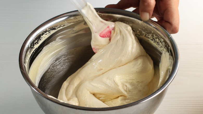 hand folding yellow batter with spatula