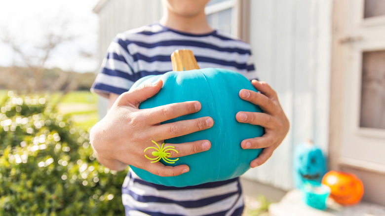 Child holding teal pumpkin