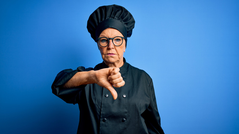 A chef holding a thumbs down 