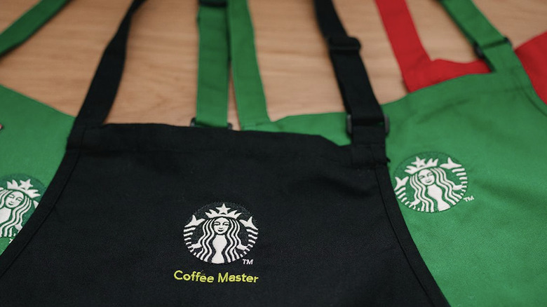 Black, green, and red Starbucks aprons on wooden table