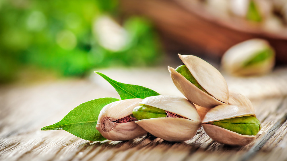 Pistachios with leaves on wooden table