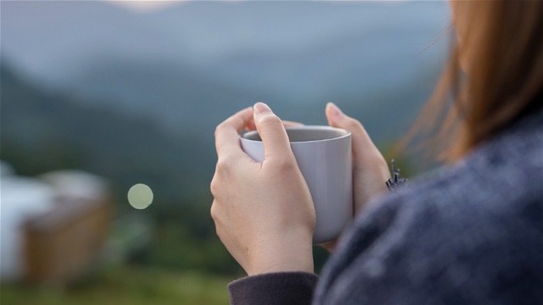 Woman holding mug with both hands outside