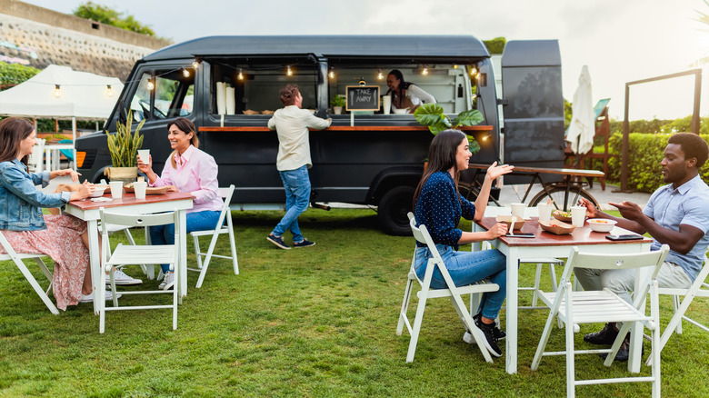 customers outside a food truck sitting at tables