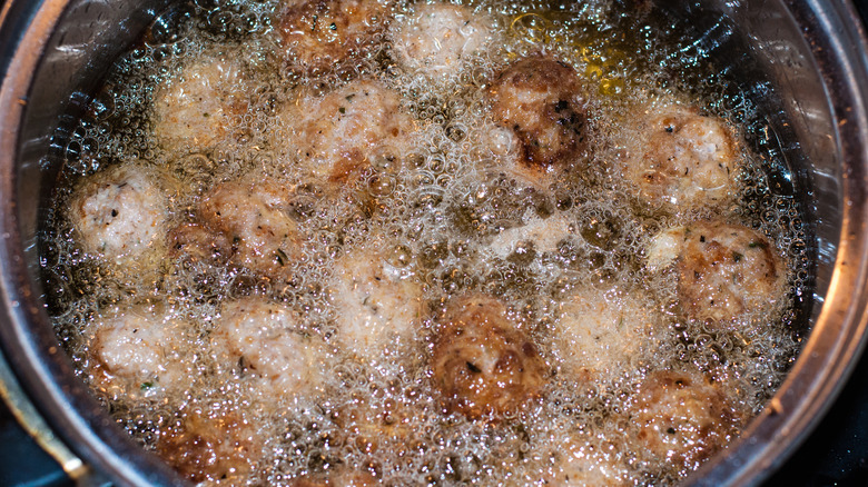 Meatballs being fried in oil