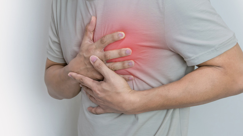 person experiencing heart attack clutching chest