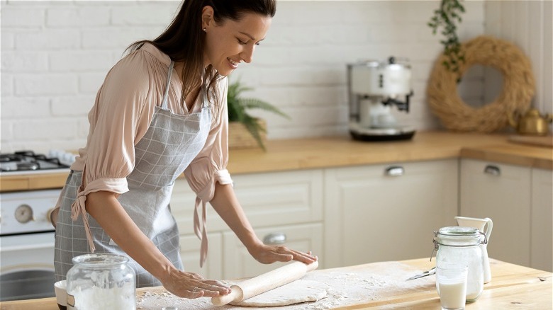 Woman rolling out dough in apron 