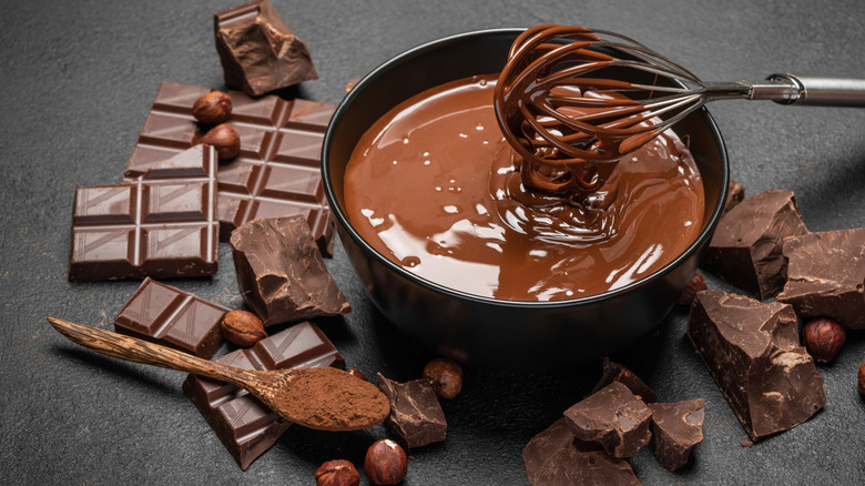 Bowl of melted chocolate with whisk and hard chocolate pieces