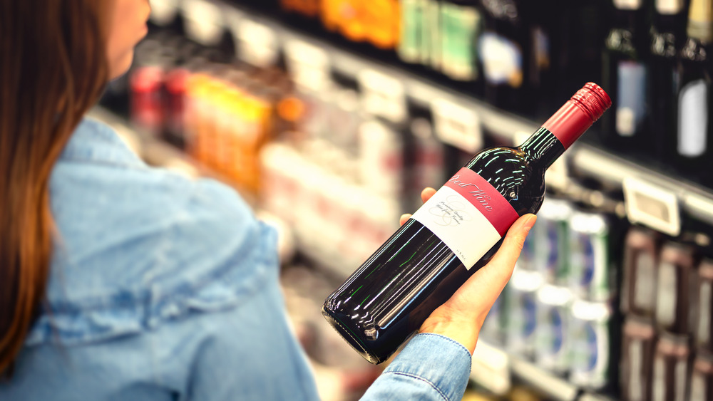 Woman examining supermarket wine