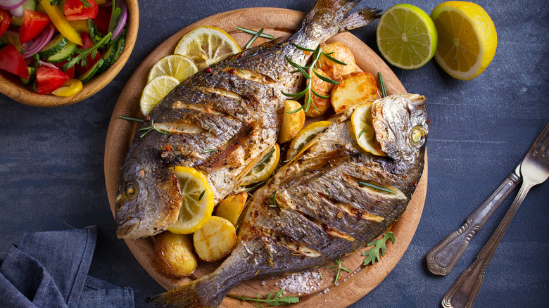 A plate with grilled whole fish and lemons