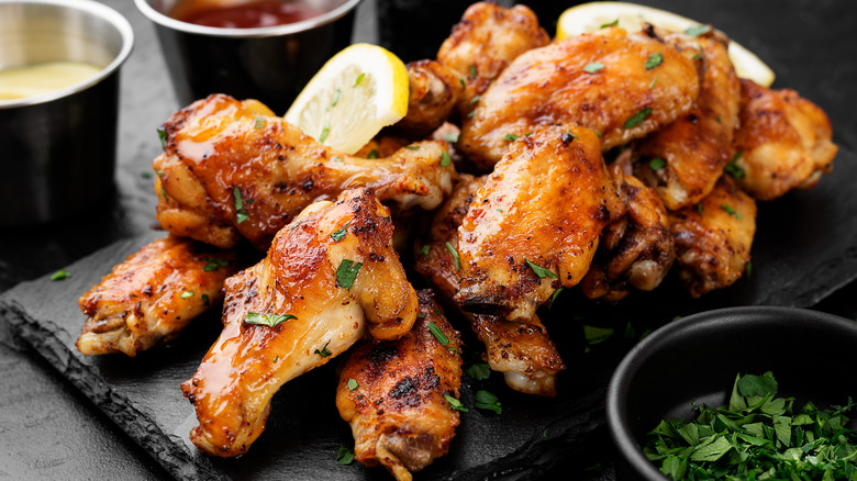 Chicken wings with lemon and herbs on black slab