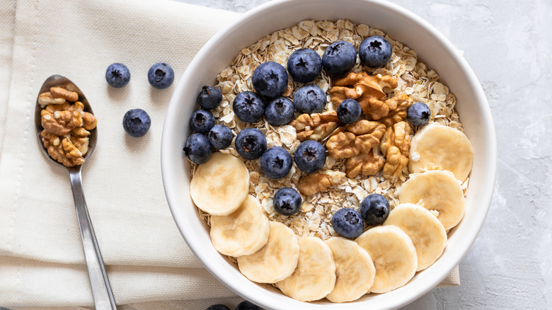 Bowl of oats topped with bananas, walnuts, and blueberries