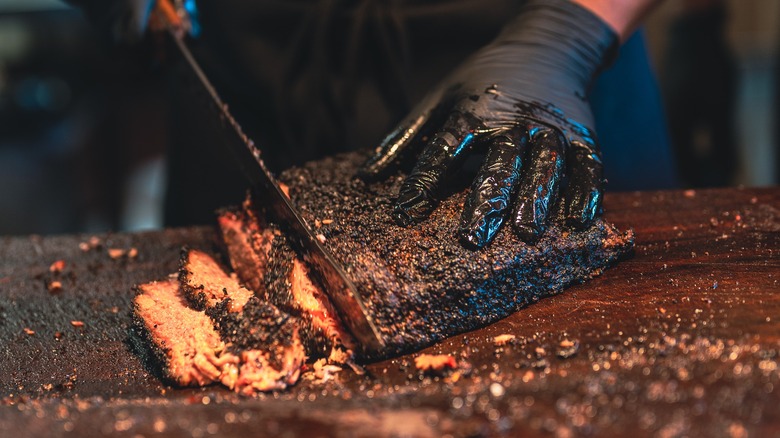 Gloved hand slicing brisket