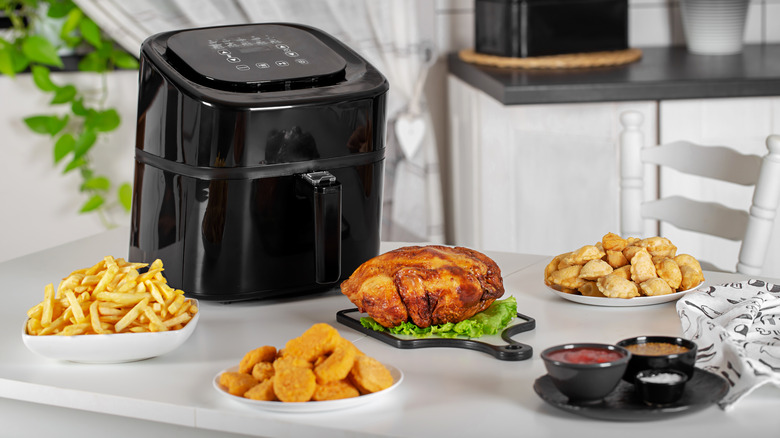 Black air fryer with different foods on the table