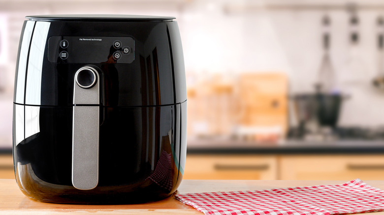 black air fryer on kitchen table with gingham cloth