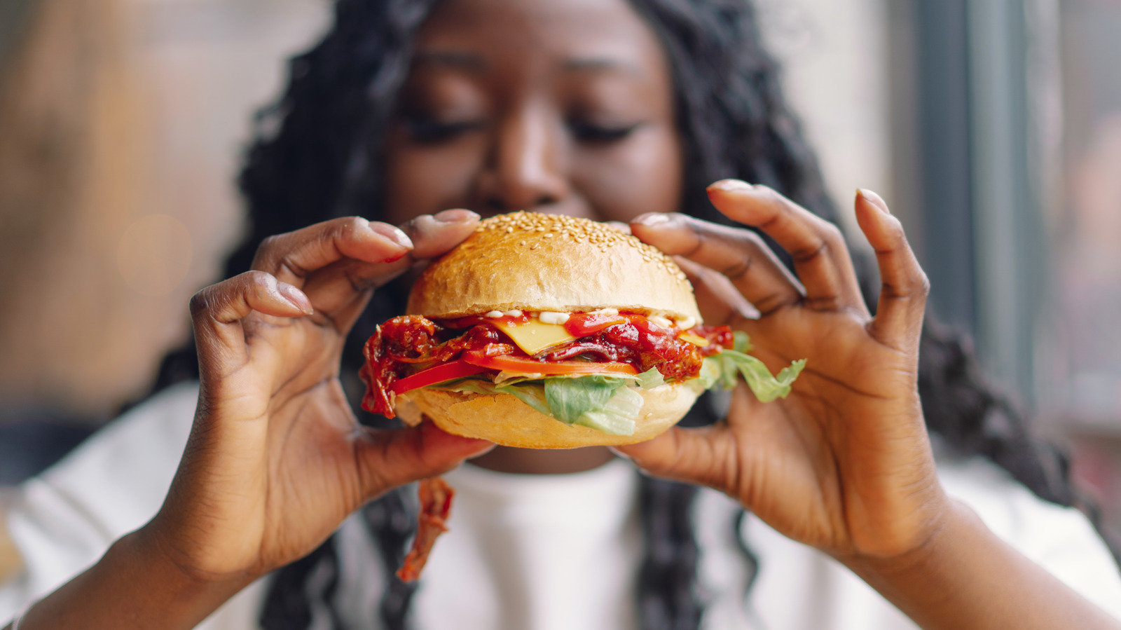 a-hamburger-with-lettuce-and-tomatoes-next-to-french-fries-on-a-black-plate