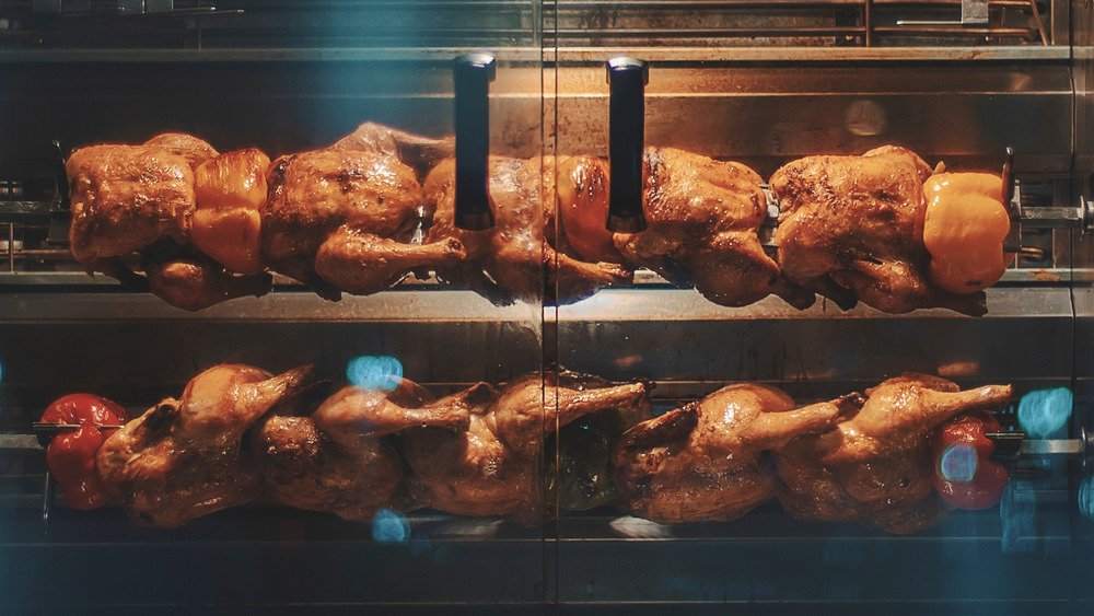 A set of rotisserie chickens rotating and cooking. 