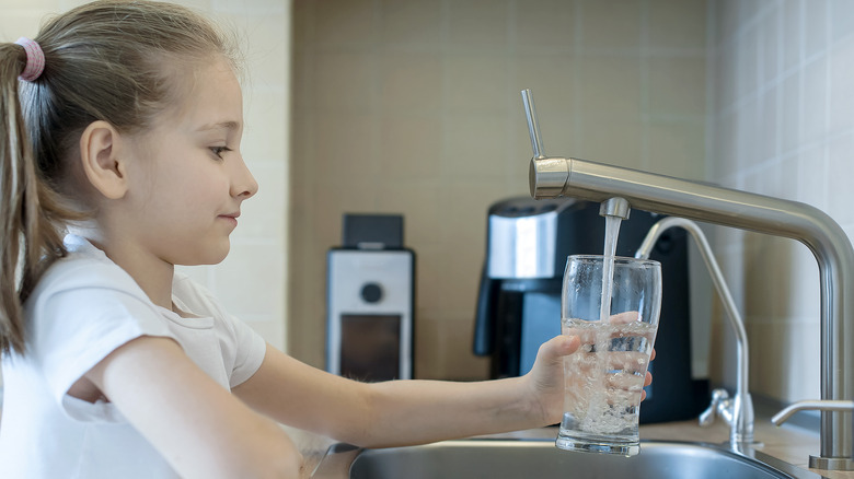 Little girl getting water from the kitchen faucet