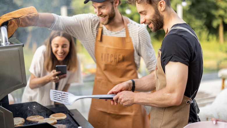 People laughing in front of an open grill