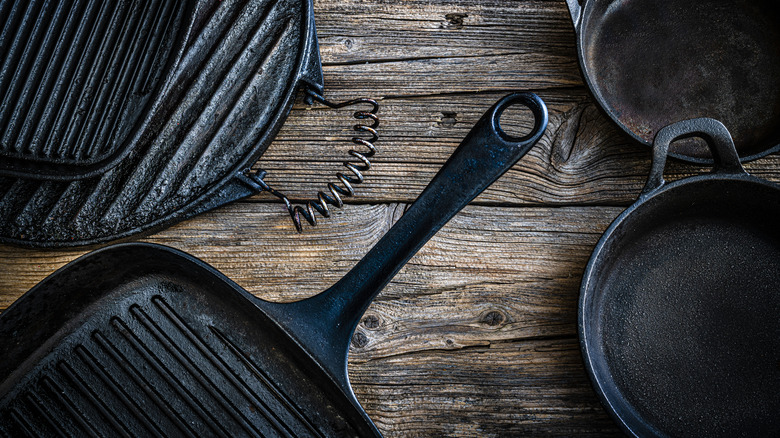 Cast iron pans on wood background