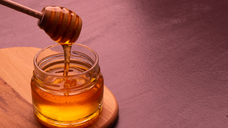 honey in glass jar with wooden dowel