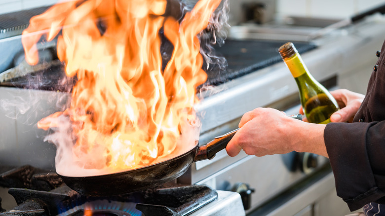 chef cooking with wine causing a flame on the stove