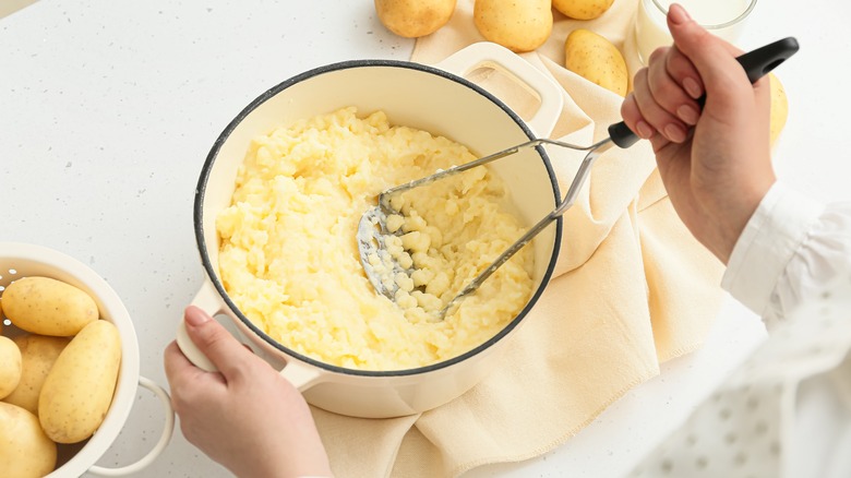 Close up of person mashing potatoes in a pot