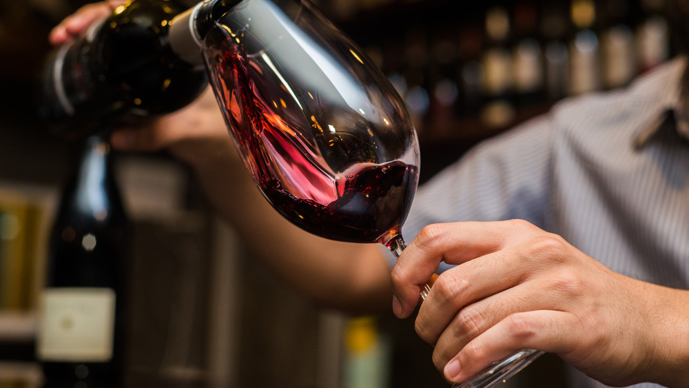 Waiter pouring red wine into a glass 