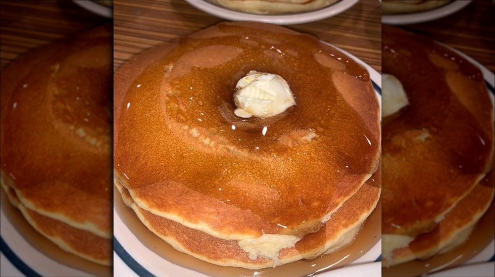 Stack of pancakes topped with butter and syrup