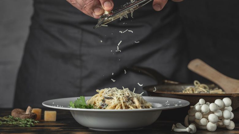 grating parmesan over pasta