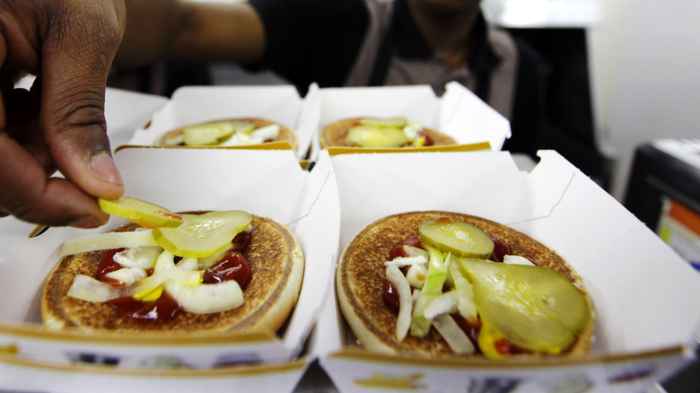 Pickles being placed on buns