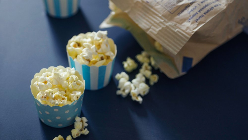 microwave bag of popcorn with two cups filled with popcorn