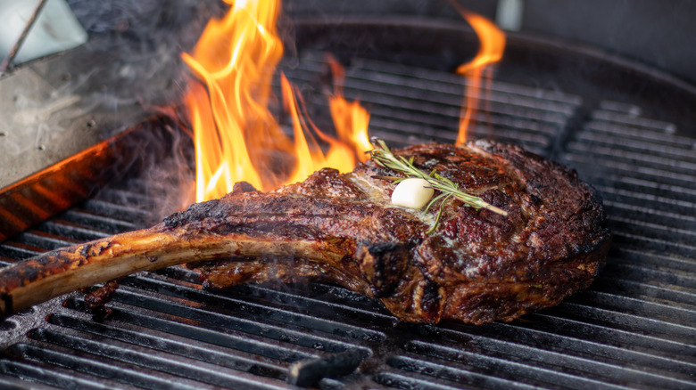 Tomahawk steak on open grill with fire