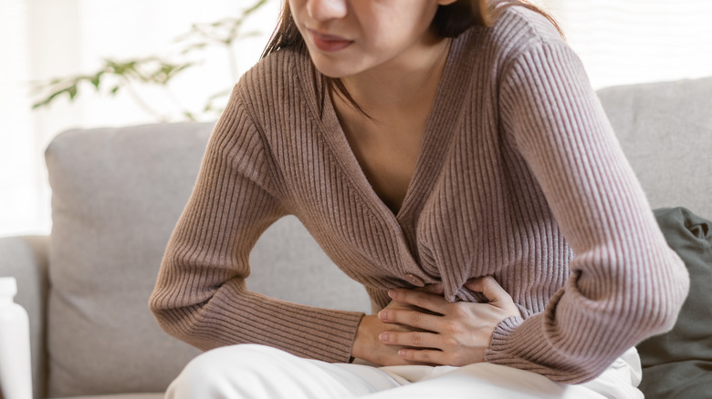 Woman holding stomach and grimacing