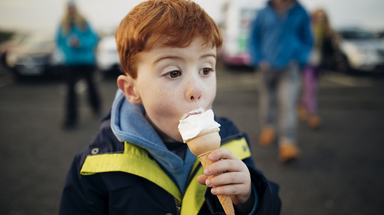 Child with red hair eating ice cream cone