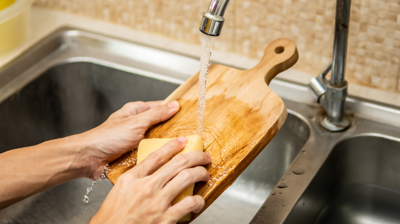 Person washing cutting board in sink